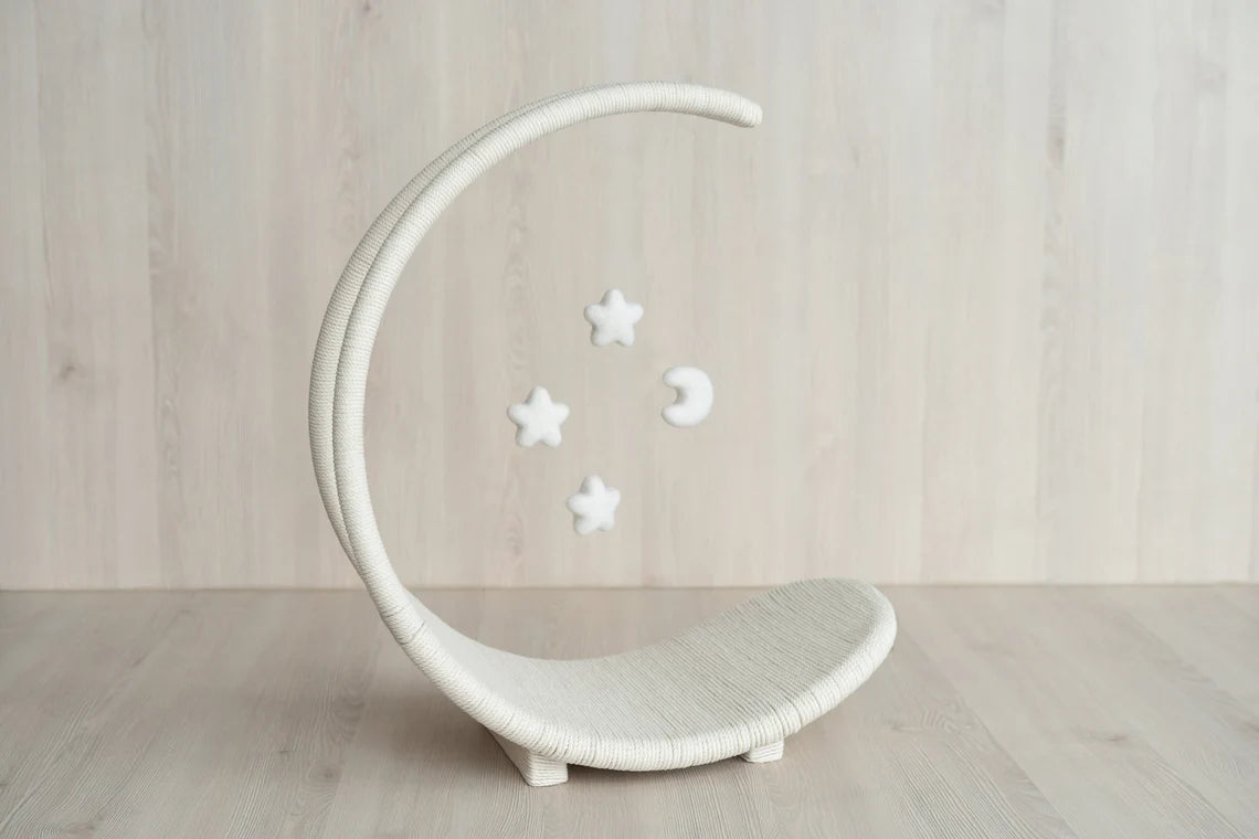 White crescent moon-shaped cribbage with decorative stars on a wooden floor.