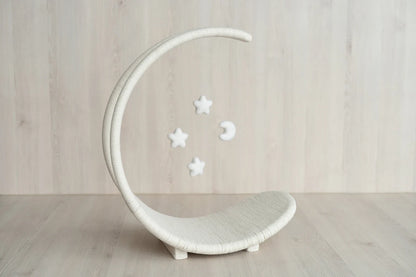 White crescent moon-shaped cribbage with decorative stars on a wooden floor.