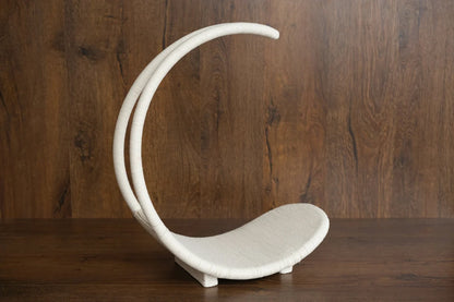 White ceramic crescent moon-shaped object on a wooden surface with a wooden background
