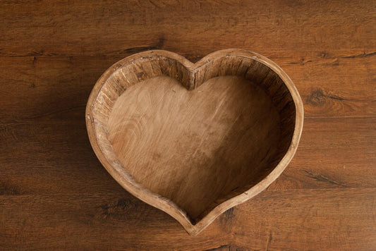 Wooden heart-shaped bowl on a wooden surface
